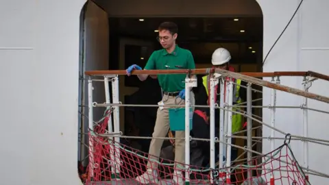 EPA/Shutterstock A man washing a handrail on the exterior of the ship
