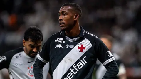 Rayan looking while stood on the pitch with his hands on his hips