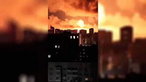 Explosions light the sky orange over a cityscape.