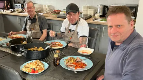 A group of veterans around a kitchen table learning cooking skills.