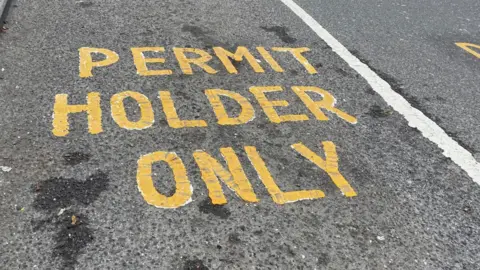 BBC/Simon Thake Yellow painted marking with the words, "permit holders only"