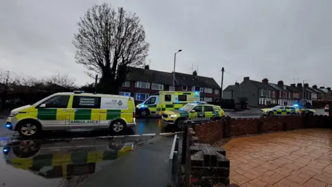 Emergency vehicles block a road in Harwich. There are two police cars and three ambulances