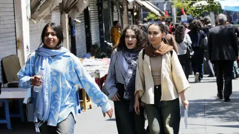 Young women walking down a busy shopping street in Tehran