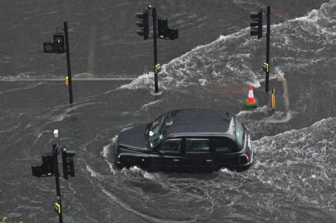 Black cab driving through floodwater
