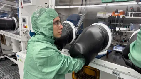 Kateryna operates a "glove box" where she puts her arms through rubber gloves to carry out a semiconductor experiment.