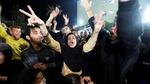 Reuters Palestinians react to news on a ceasefire deal with Israel, in Deir al-Balah, central Gaza (15 January 2025)