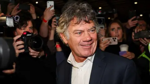 Reuters Gerard Hutch in a navy blazer and white shirt, smiles at the RDS counting center with the crowd in the background