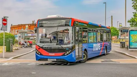 A blue and red More bus turning on the road.