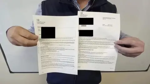 Anonymous Anonymous man holding a letter from HMRC with sensitive information blacked out