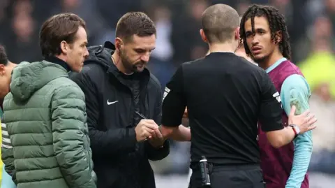 Hannibal Mejbri talks to match referee Andrew Kitchen as fourth official John Busby takes notes and manager Scott Parker looks on