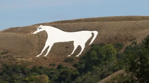 A large white horse carving on a dry hillside. 