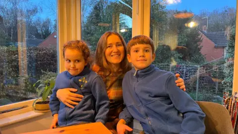 Ukrainian woman with her two young children either side posing for a photo