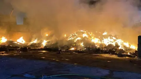 ECFRS A large pile of waste on fire at night.