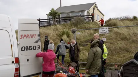 Shaun Whitmore/BBC People evacuating one of the homes in Hemsby on Monday morning