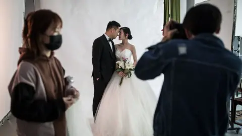 Getty Images A couple pose for wedding photos at the Pushi wedding photography studioApril 15, 2020 in Wuhan