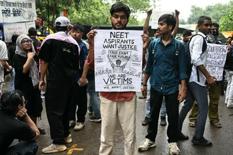 AFP via Getty Image A Cockroach Janta Party (CJP) supporter holds a placard at Jantar Mantar in New Delhi on July 22, 2026 during the ongoing protest to demand the resignation of India's Education Minister Dharmendra Pradhan over alleged NEET exam irregularities. 