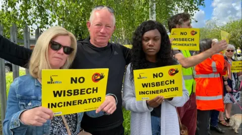 Emma Baugh/BBC People holding yellow placards saying 'no Wisbech incinerator' on them