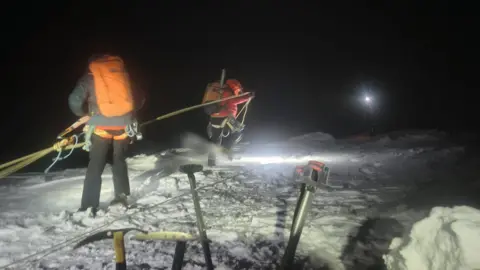 Lochaber Mountain Rescue Team Rescue team members working with ropes in snow and in darkness. 