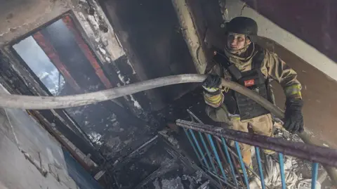 Ukrainian emergency service workers extinguish a fire in a residential building, after Russian shelling, in Kostiantynivka