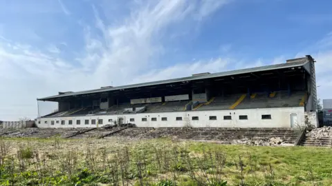 PA Media A derelict stand in Casement Park. There is a blue sky in the background.
