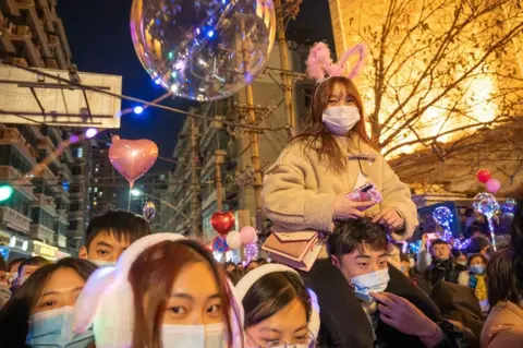 Getty Images People attend New Year bell-ringing ceremony in front of Hankow Customs House during New Year's Eve celebrations on 31 December 2020 in Wuhan, Hubei Province of China