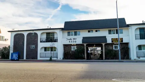 A row of white apartments in a block with a black roof, in Hollywood, Los Angeles