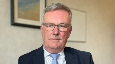 PA Media Mike Nesbitt who has grey hair and glasses looking straight into camera