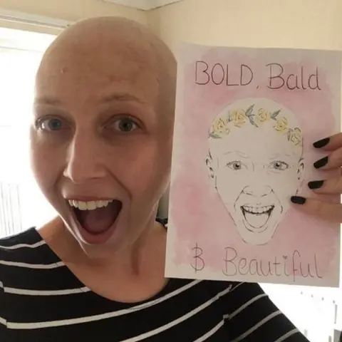 Kirsty Hopgood Kirsty Hopgood holding a 'bold, bald and beautiful' card