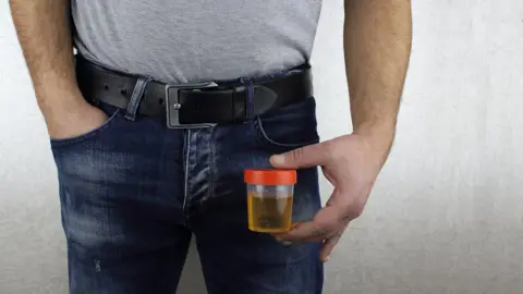 Getty Images Man holding a urine sample