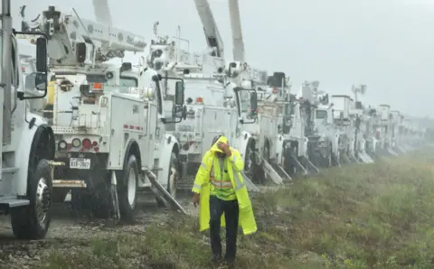 Stephen M. Dowell/Orlando Sentinel/Tribune News Service via Getty Images Charles Starling, a lineman with Team Fishel, is pelted with rain as he walks by a row of electrical line trucks staged in a field in The Villages, Florida 