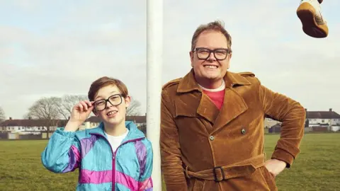 Oliver Savell and Alan Carr pose on a football pitch in a promotional image for Changing Ends