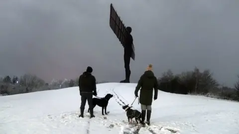 Owen Humphreys/PA Dog walkers at the Angel of the North