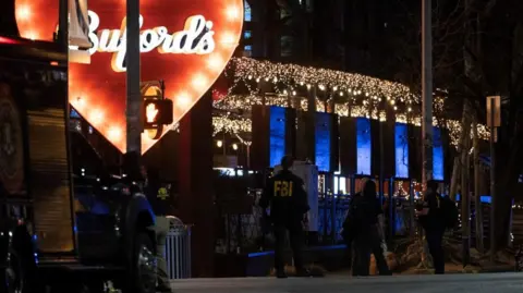 The bar Buford's is written in cursive inside a huge red heart while FBI agents search the outside.