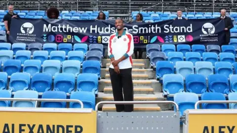 Birmingham 2026 Matthew Hudson-Smith pictured standing in front of a banner with the name of the stand