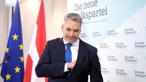 Getty Images Austria's Interior Minister Karl Nehammer leaves a press conference after he was named as new party head and also as Austria's new chancellor in Vienna on December 3, 2021