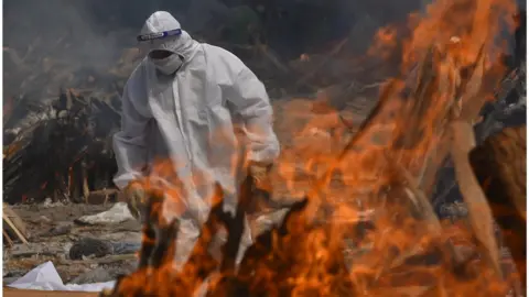 Getty Images A Family member, wearing a Personal Protective Equipment (PPE), performs the last rites for COVID-19 victims