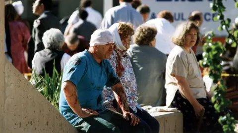 Shutterstock A man and woman with bloody injuries sit among others outside bomb scene