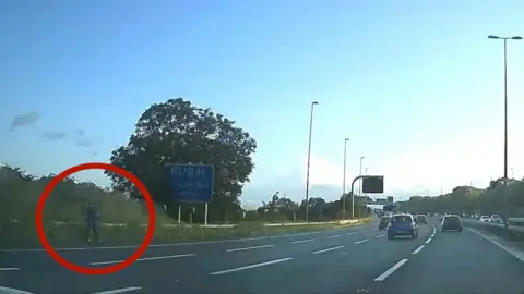 BBC Dashcam footage showing a person riding an e-scooter up the slip road of the M5 Northbound near J19