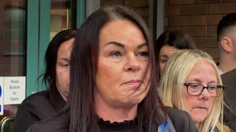 PA Media A woman with long dark hair speaks to the media outside Sheffield Coroner's Court.