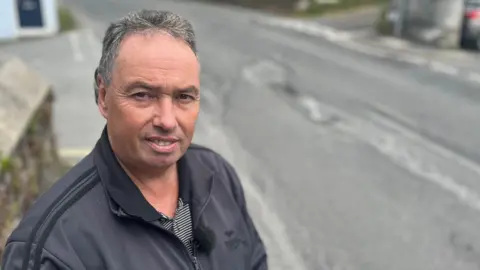 BBC Dave Newcombe next to a pothole