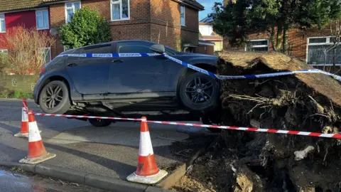 Matt Marvel/BBC A car lifted off the ground by fallen tree roots