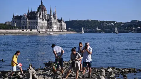Getty Images People walk on the dried-out waterbed of the river Danube under the Margaret Bridge in downtown Budapest, Hungary, on July 30, 2026. The water level of the Danube in the capital Budapest was measured at 23 centimeters, which is close to the lowest values ever recorded.