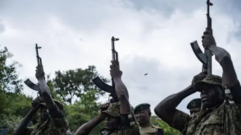 Badru Katumba/AFP Afbeelding van Oegandese soldaten die de Oegandese marathonloper Rebecca Cheptegei groeten tijdens haar begrafenisceremonie in het Bukwo-district, Oeganda - zaterdag 14 september 2024.