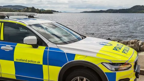 A police car parked at the edge of Loch Lomond