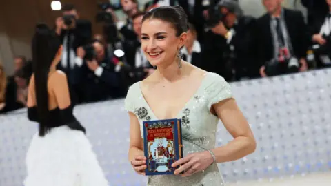Getty Images Chloe Malle stands on red carpet holding book in her hands