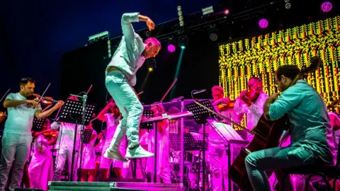 Guy Peterson A man jumping on a brightly coloured stage