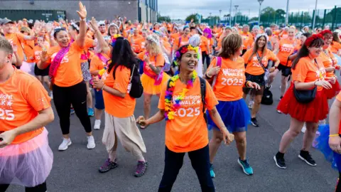 Prospect Hospice People smiling and stood in orange 'starlight walk' t-shirts.
