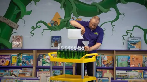 PA Media Site manager Mark Lee fills bottles of hand sanitizer at Queen"s Hill Primary School in Costessey near Norwich