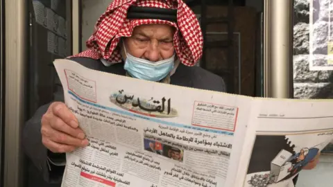 A Palestinian man reads the daily newspaper Al-Quds, in the occupied-West Bank town of Hebron, on April 4, 2021