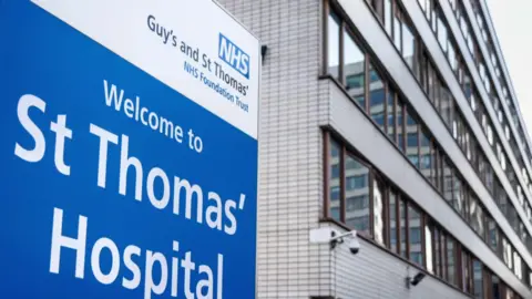 An exterior view of St Thomas' Hospital including a sign.